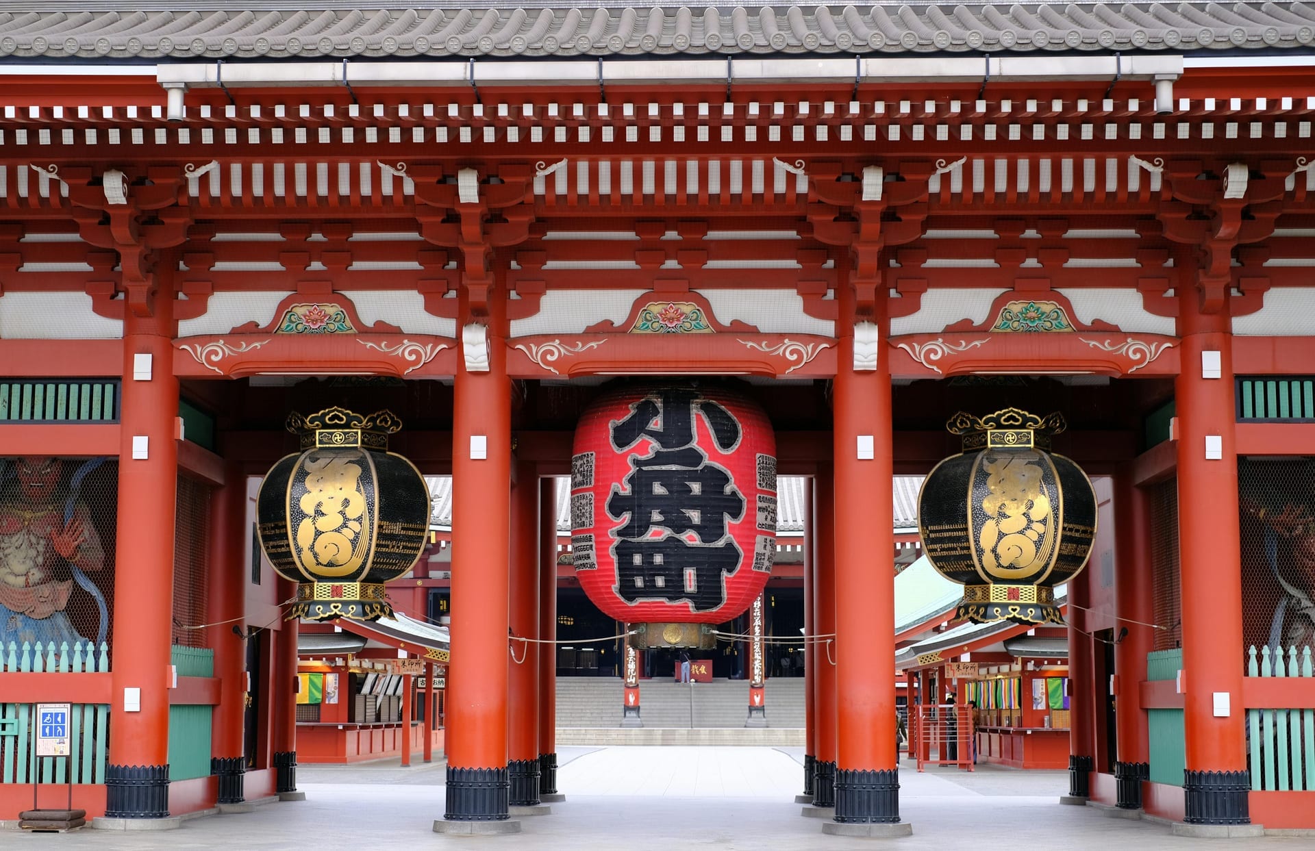Close-up of Hozomon Gate at Senso-ji showing red pillars, ornate lanterns, and guardian statue murals